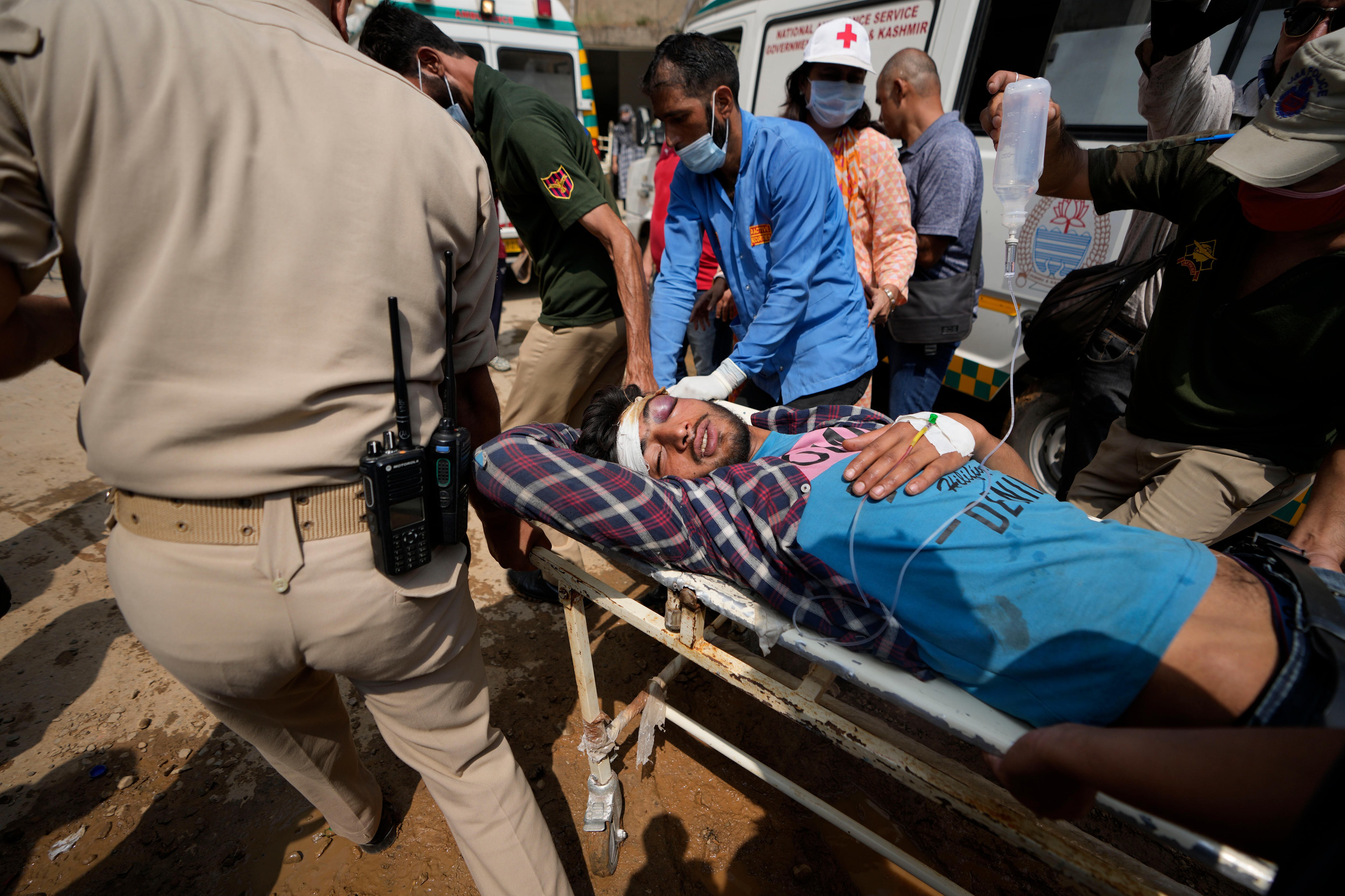 An injured man with a bandaged head is wheeled on a stretcher by several men.