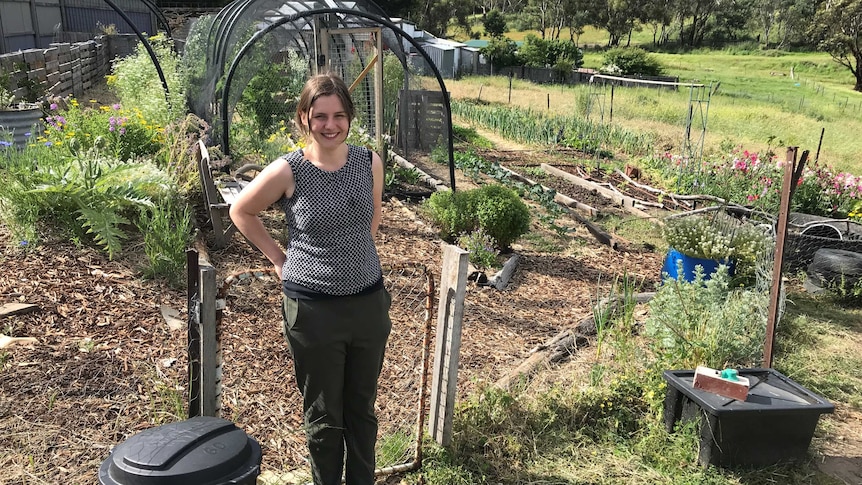 Elicia Casey-Winter standing in her very impressive permaculture garden, surrounded by growing veggies.