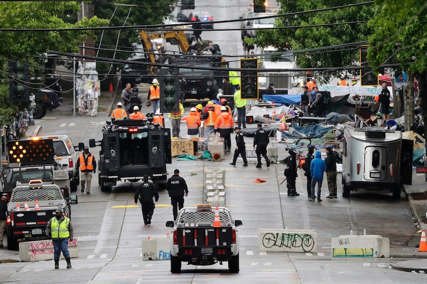 Heavy machinery removes debris and barriers from a street.