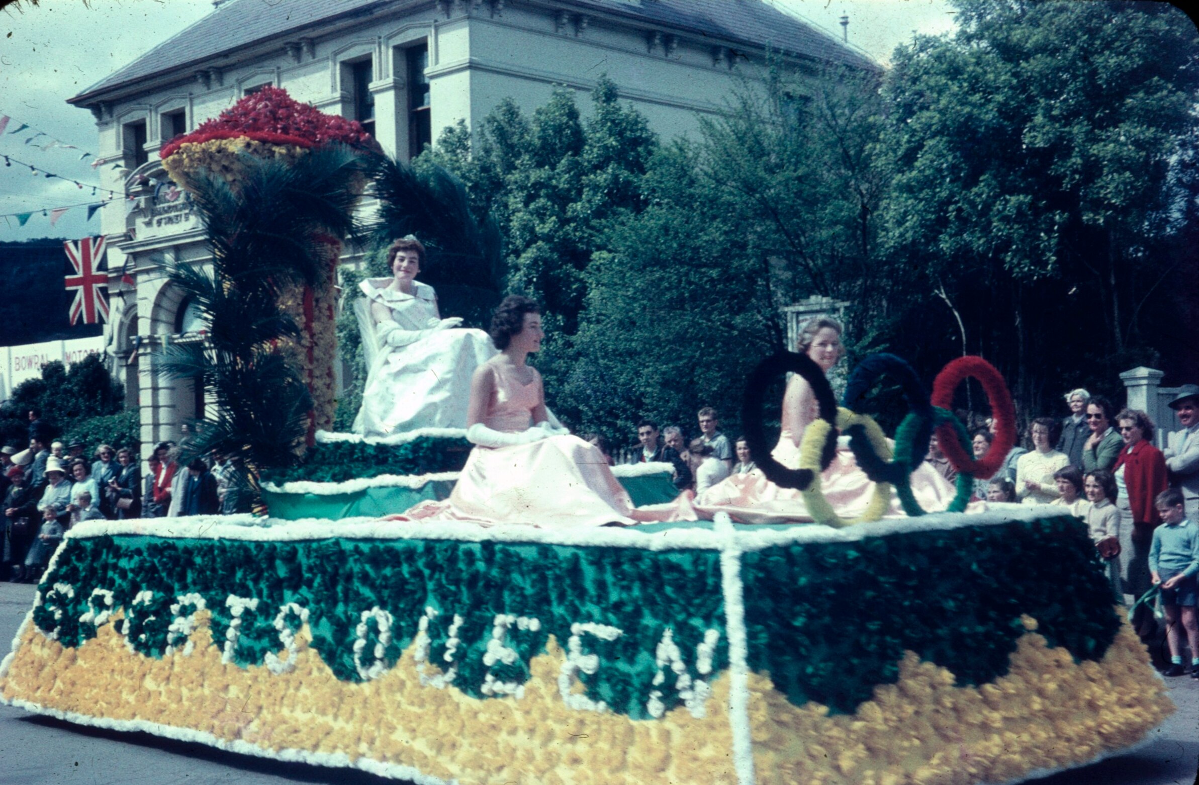 A black and white shot of a street in Bowral with a flower parade passing by in 1959.