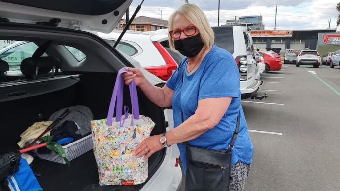 Anda Hamilton stands in car park putting bag of shopping in her car boot