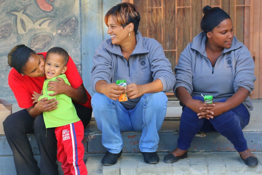 Three women and a young boy sitting on a step.