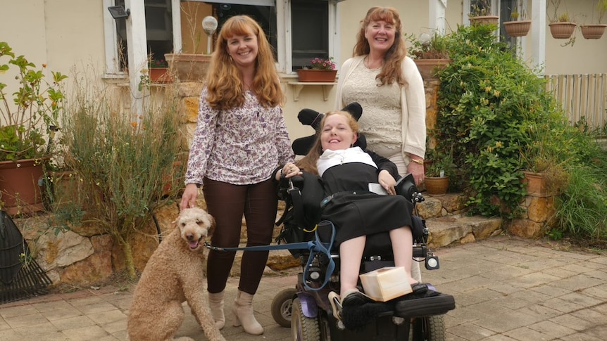 Eleanor Beidatsch pictured outside a house with two women and a dog.