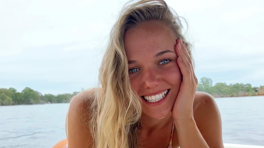 a young woman smiling and leaning her head on her hand while on a boat out on the water