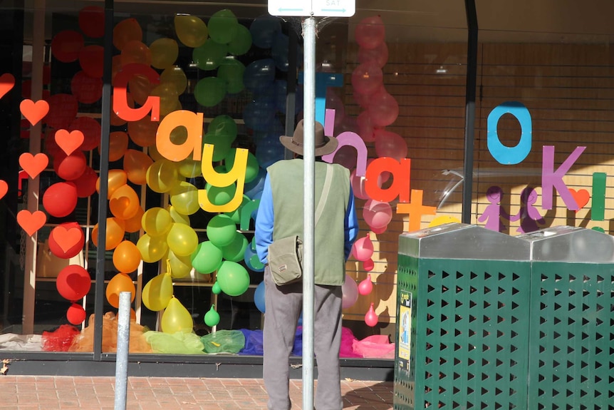 Man looking at pharmacy window display in Hamilton.