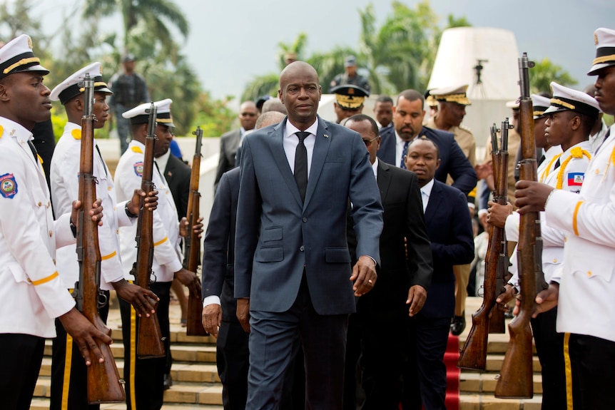 Jovenel Moise walks past a military guard 