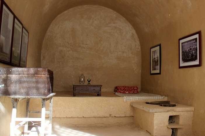 A cave dwelling with back and white photos aligning the right hand side of the wall.