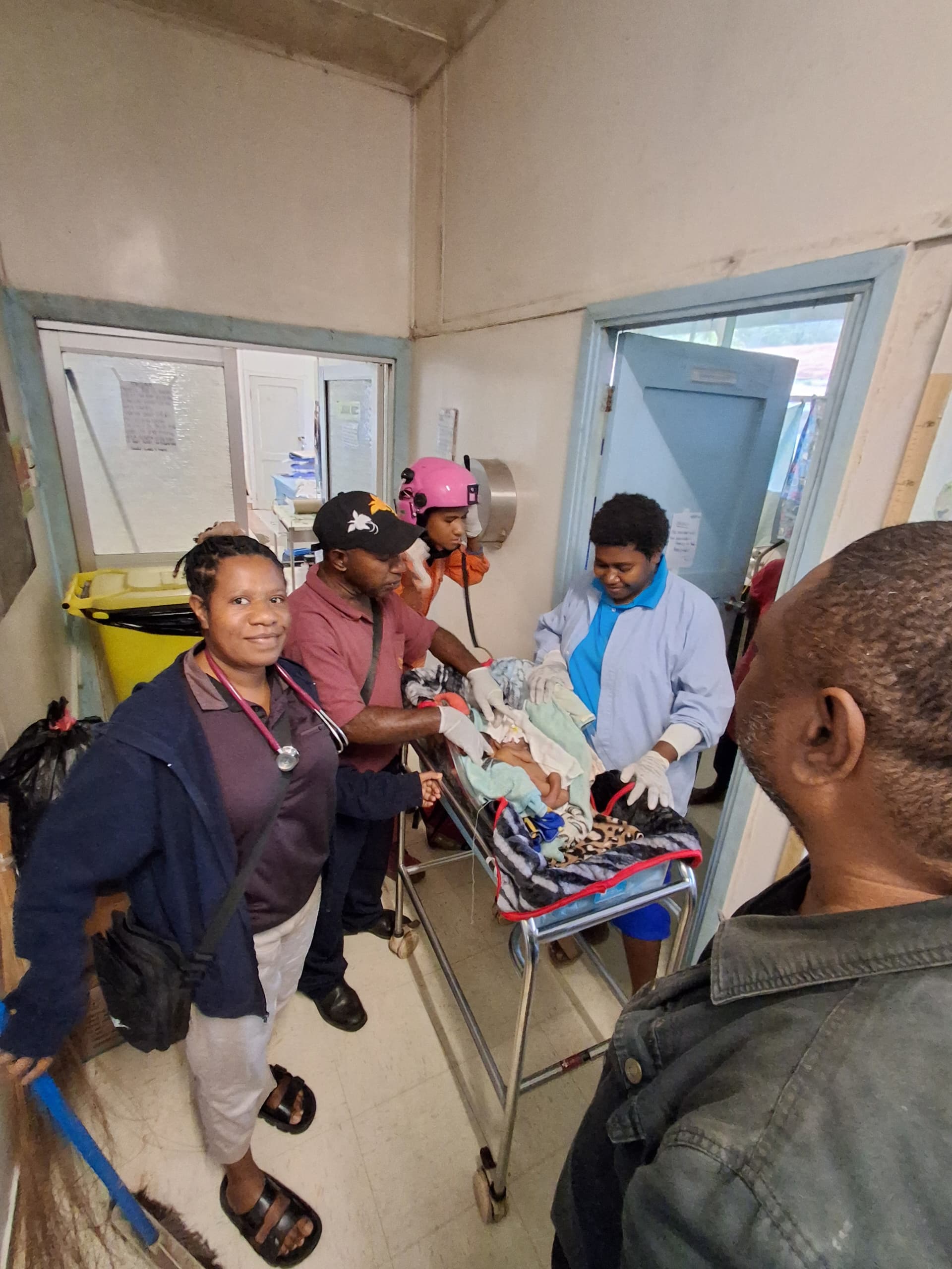 Two newborn conjoined twins lie in a small hospital stretcher as medical specialists look on.