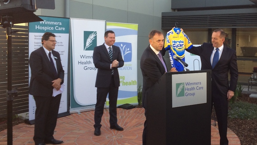 Wimmera Health Care Group CEO Chris Scott presents Prime Minister Tony Abbott with a blue and yellow Horsham bike top