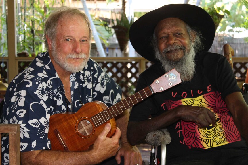 Karl and Baamba sitting beside each other, with Karl holding a ukelele