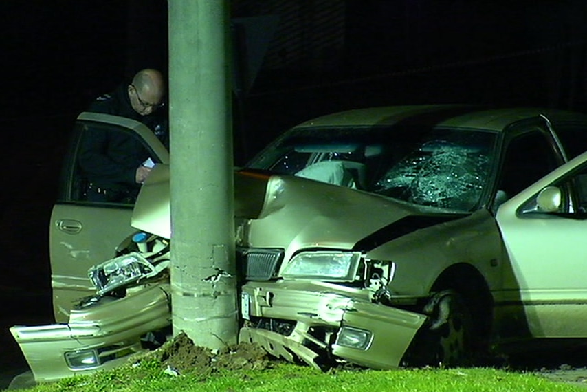 A police officer examines the wreckage of a car that hit a pole at Hampton Park.