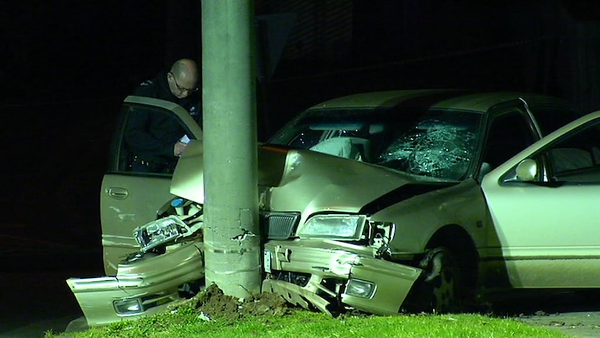 A police officer examines the wreckage of a car that hit a pole at Hampton Park.