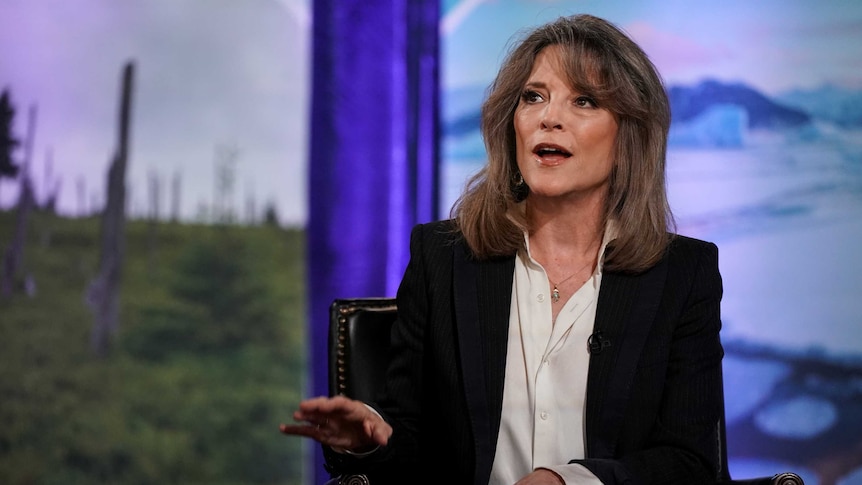 Democratic presidential candidate Marianne Williamson wears a black jacket and white shirt and talks.