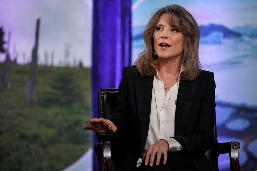 Democratic presidential candidate Marianne Williamson wears a black jacket and white shirt and talks.