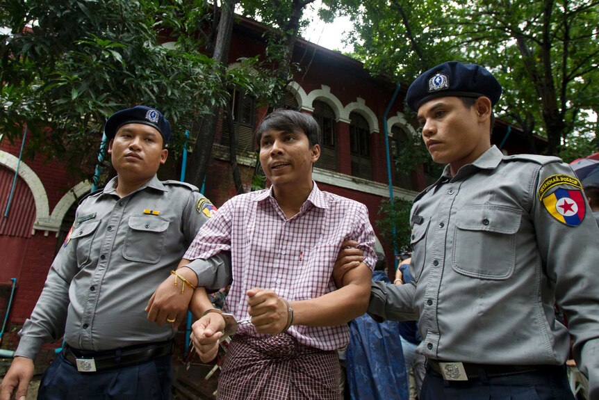 Reuters journalist Kyaw Soe Oo is escorted by two policemen.