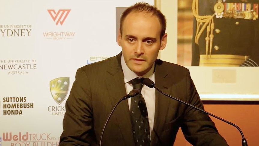 a man standing behind a lectern talking