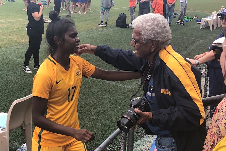 Young Matildas player Shay Evans embraces former Socceroo and Indigenous football champion John Moriarty