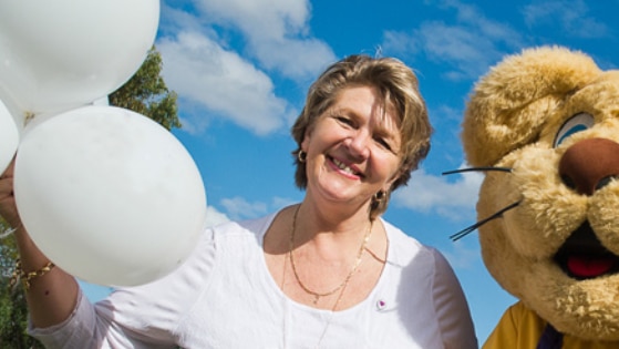 Hetty Johnston holds balloons and stands beside a teddy bear