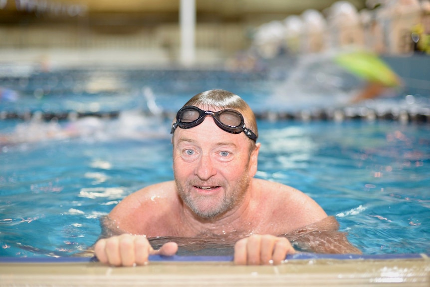 Amputee swimmer Michael Powell holds onto edge of a swimming pool with goggles on in Brisbane in July 2017