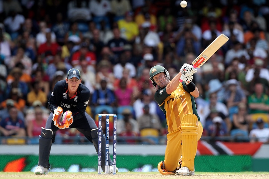 Cameron White is down on one knee after he smashes a cricket ball and it hovers in the air.