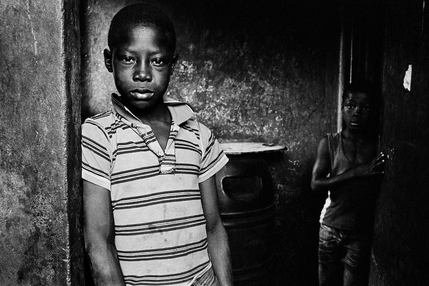 A boy of Haitian descent stares into the camera as his younger brother looks on.