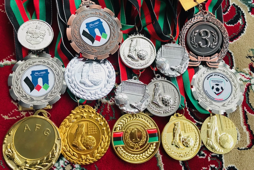 More than a dozen medals, some showing Afghanistan flag colours and soccer balls