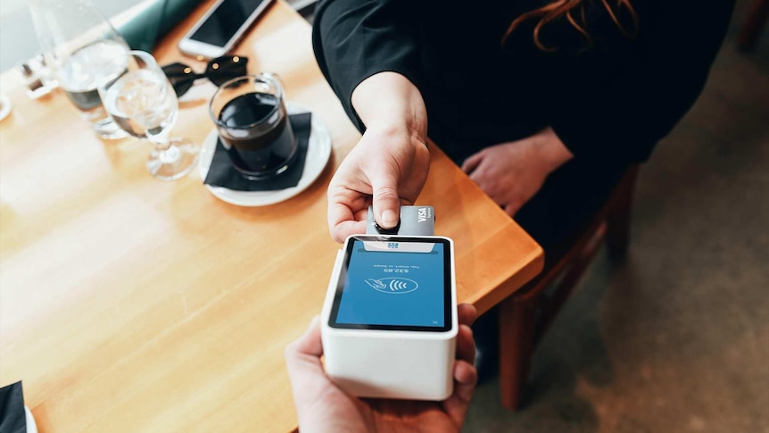 Woman in cafe paying on card on a cordless machine