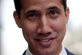 A man smirking while adjusting his navy blue suit jacket