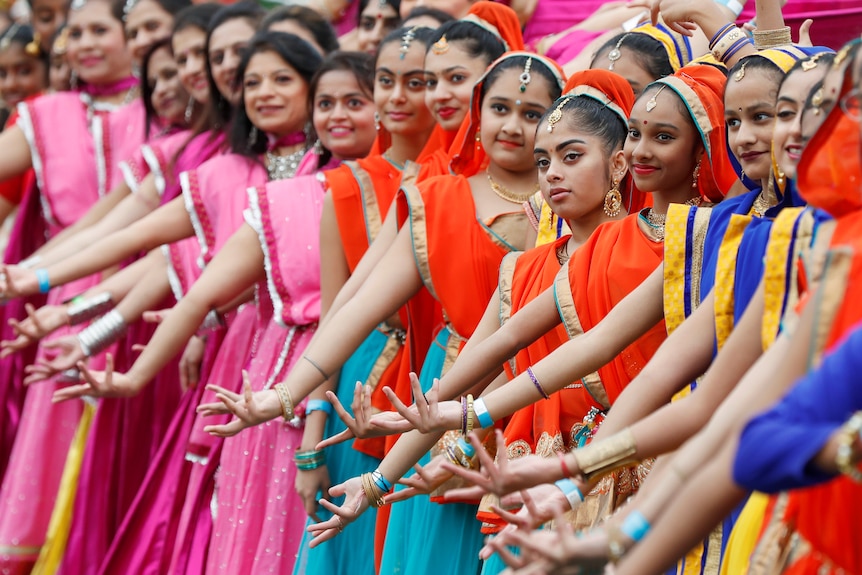 A line of dancers in traditional Indian costumes.