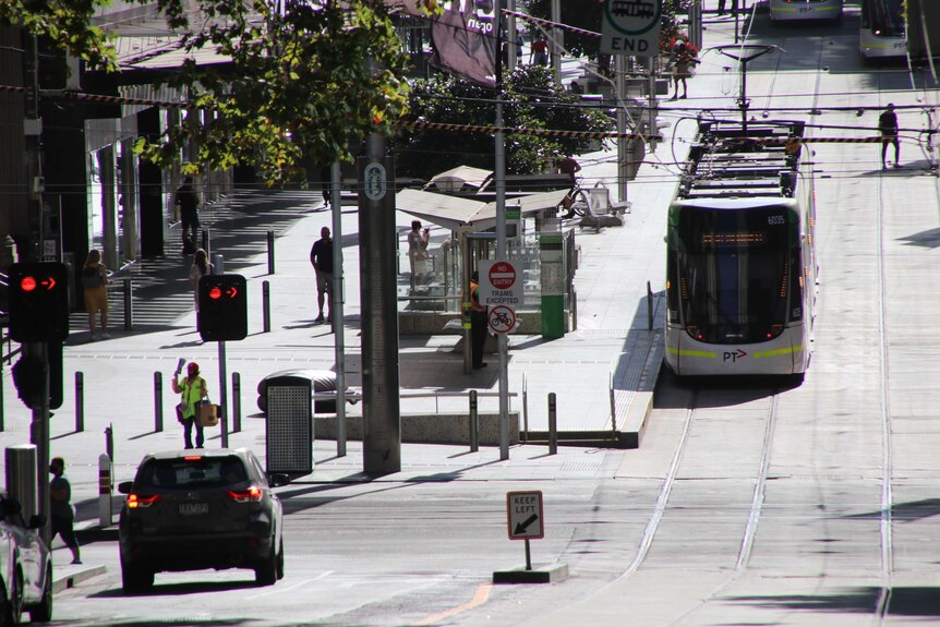 A handful of pedestrians and a tram on a quiet street in Melbourne CBD.