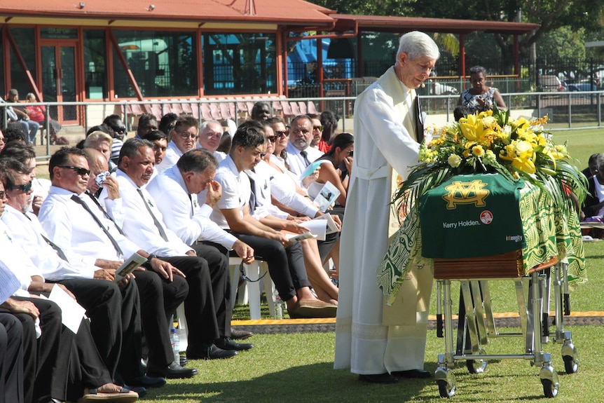 A priest puts his can on the casket of Jack Long