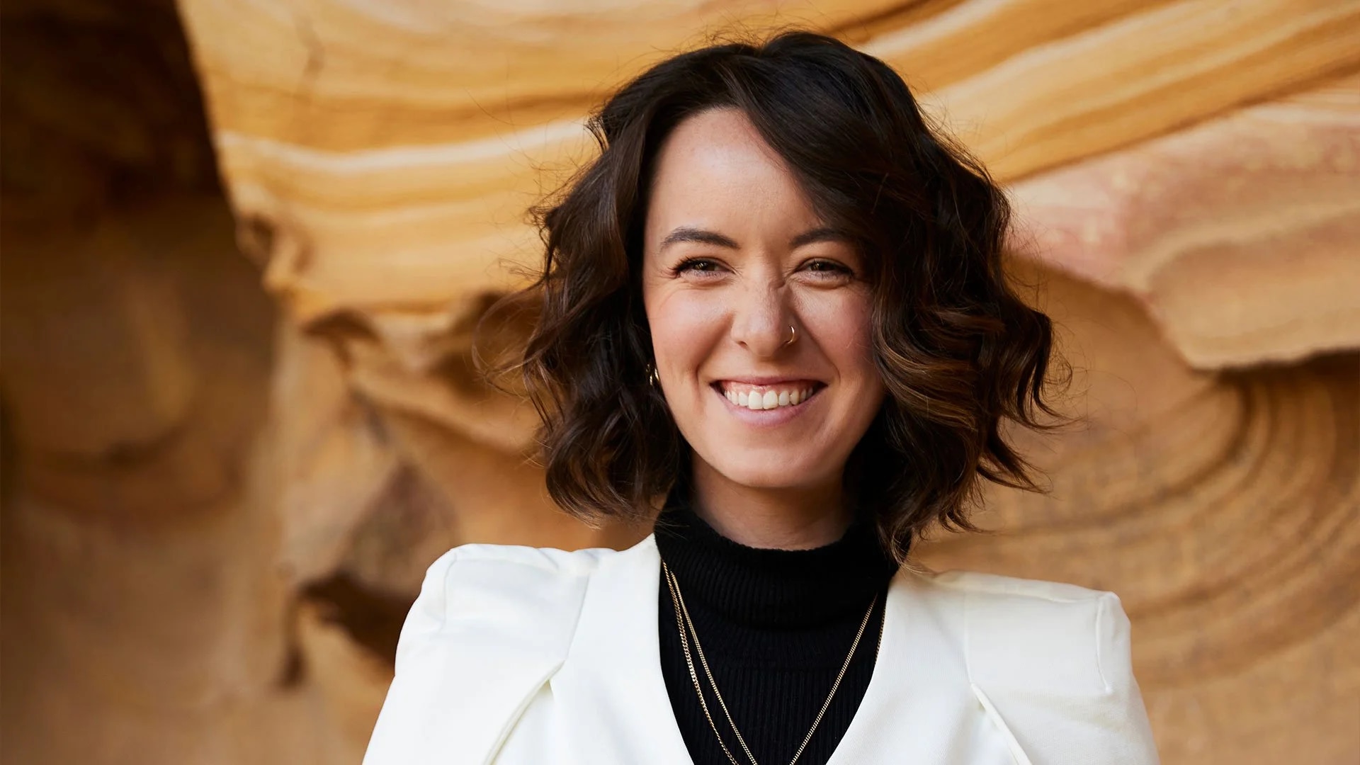 A front-on shot of vocalist Kate Wadey in w hite blazer; she's smiling at the camera