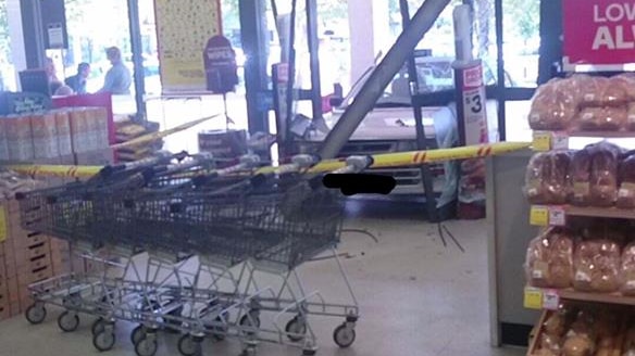 A car stuck in the smashed doorway of a Woolworth's supermarket.