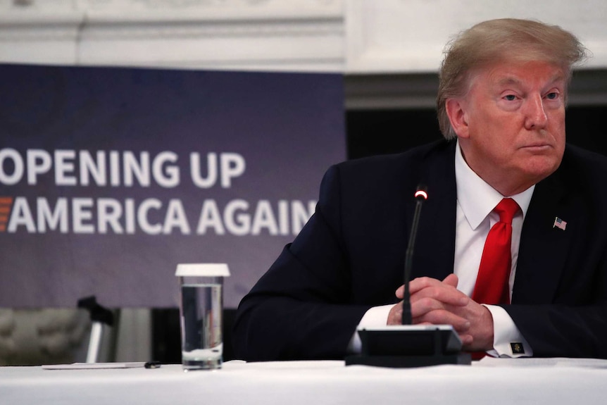 President Donald Trump listens to a question from a reporter during a roundtable with industry executives.