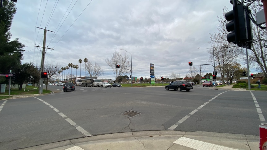 A street corner showing roads on a busy intersection, where a residential street and a highway intersects. 
