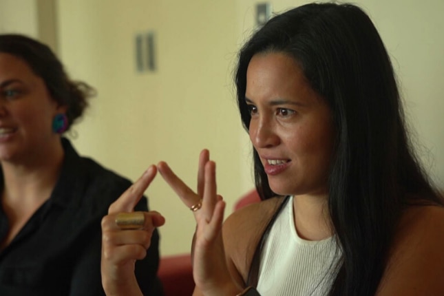 A young woman spells out a letter using Australian sign language