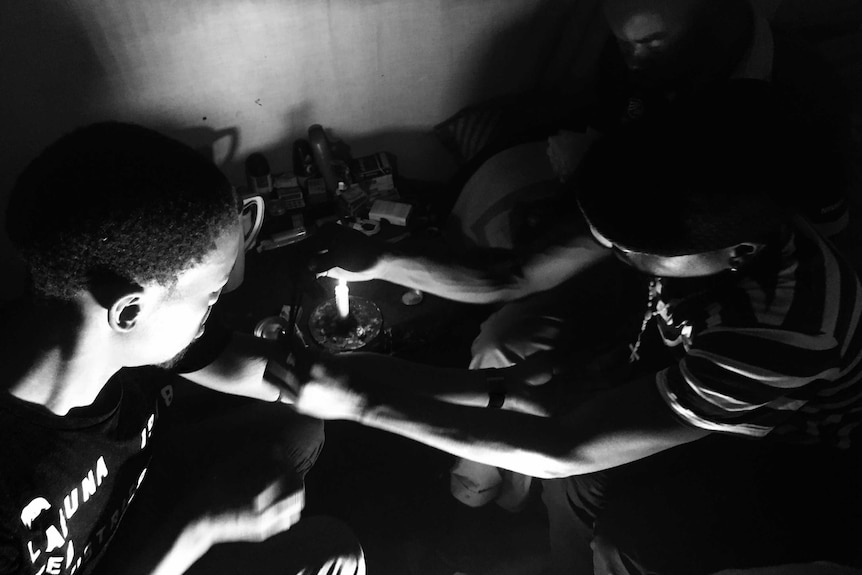 A young man injects blood into another man's arm.