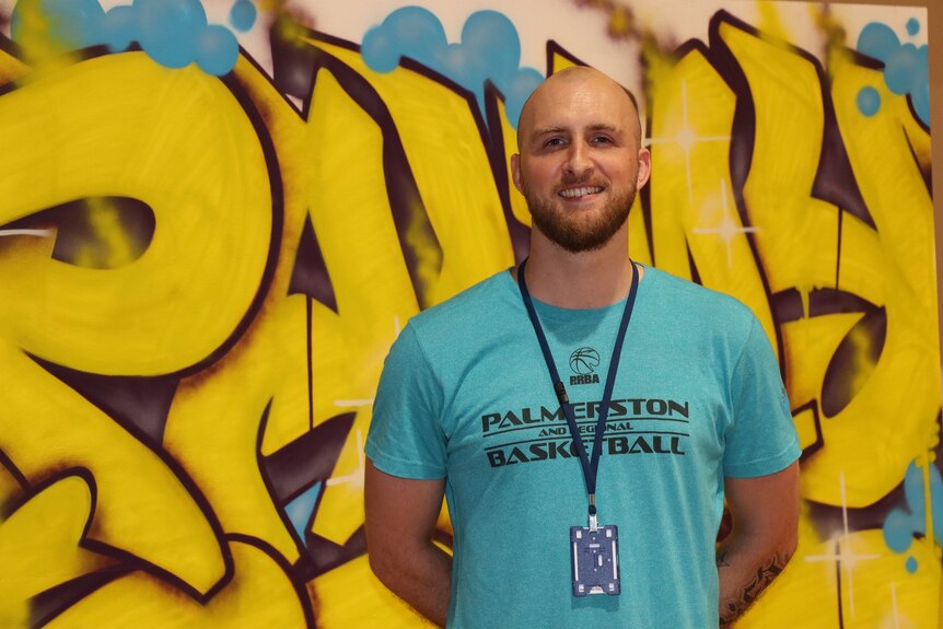 Riece Ranson stands in front of a graffiti wall.