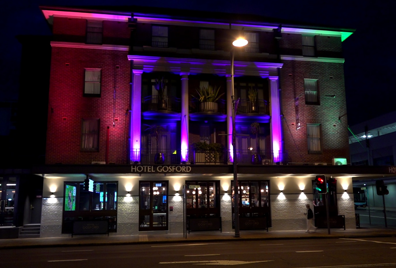 A brick building after dark, its pylons are lit up.