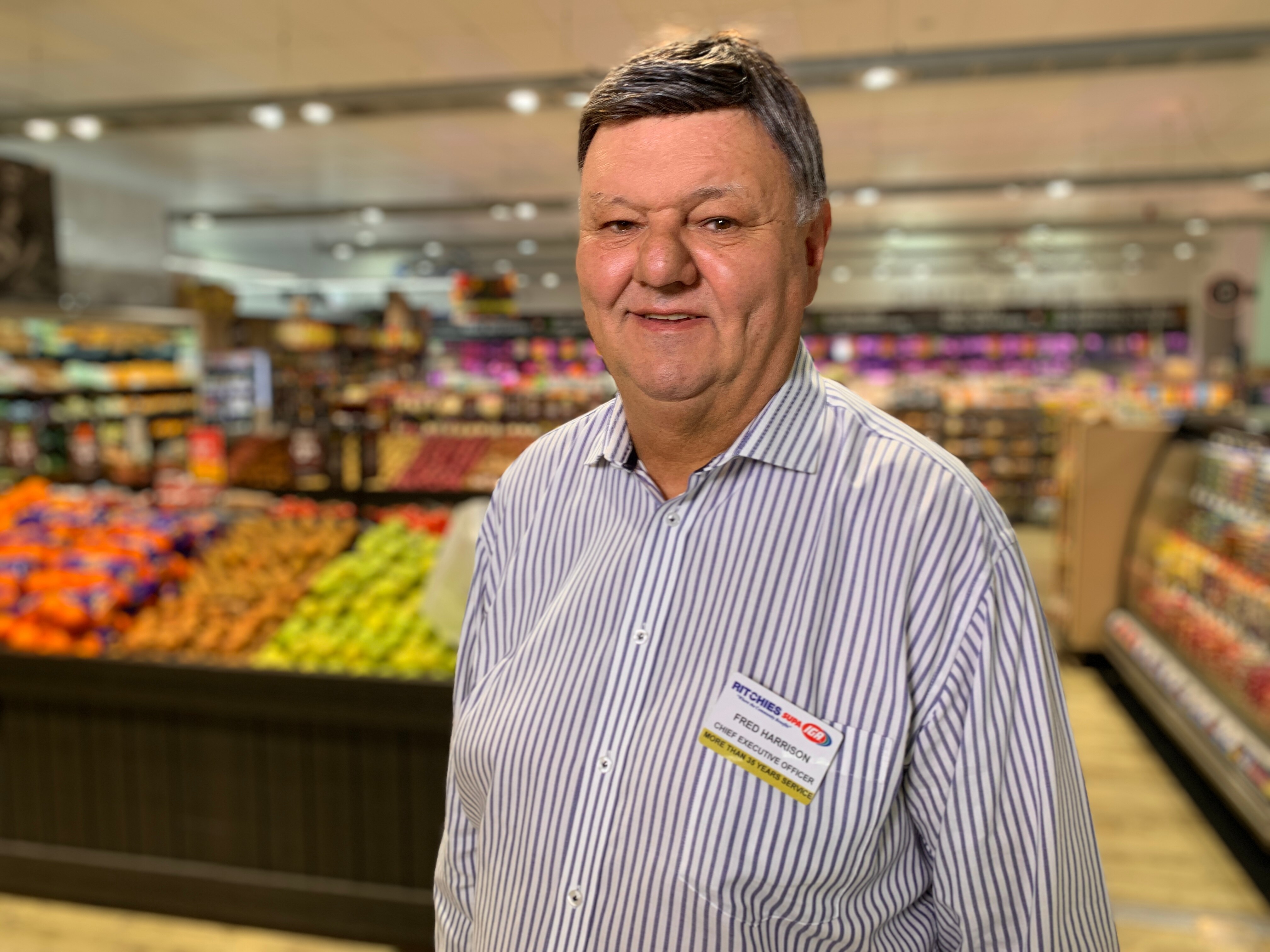 un hombre parado en un supermercado sonriendo a la cámara
