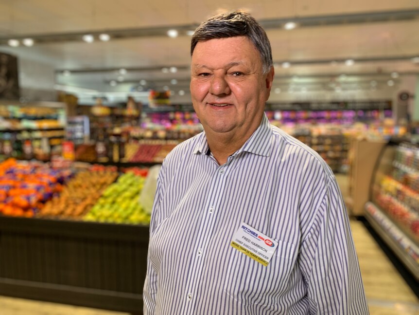 a man standing in a supermarket smiling at the camera