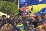 A man surrounded by Australian flags and police performs a Nazi salute