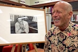 David Helfgott next to a framed photograph of himself.