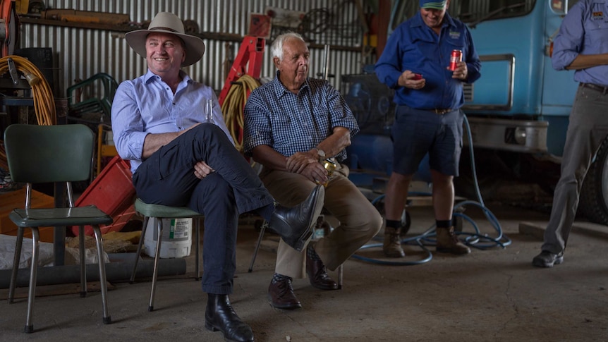 Barnaby Joyce smiles while sitting in a shed with workers