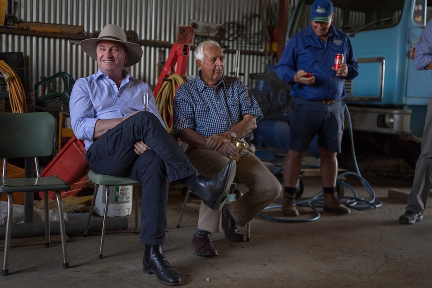 Barnaby Joyce smiles while sitting in a shed with workers