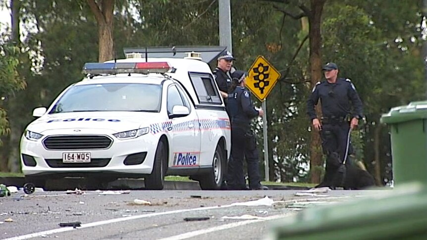 Police officers and police dog at the scene with the wreck of a car after a crash at Ashmore Road at Ashmore.