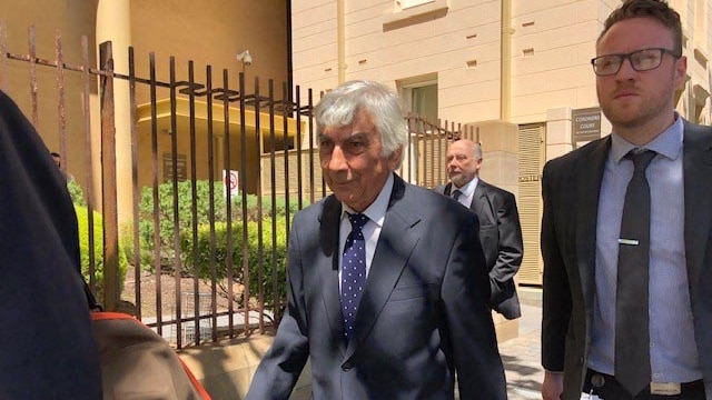 Men in business suits walking outside the Coroner's Court.