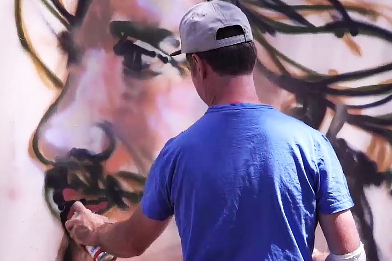 James Cochran works on a portrait with aerosol paint