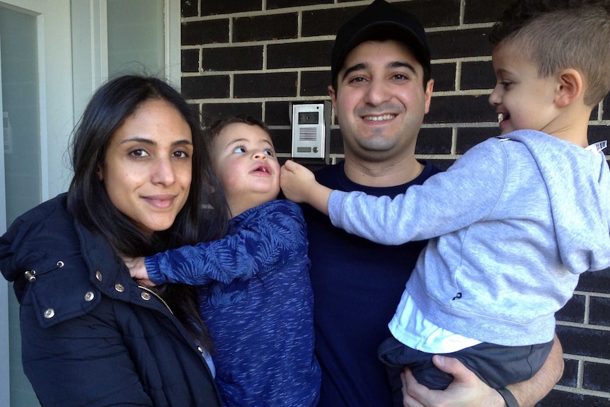 Noura (left) and Nasser Hojok, holding their two children outside the door of their home at Wollert Victoria.