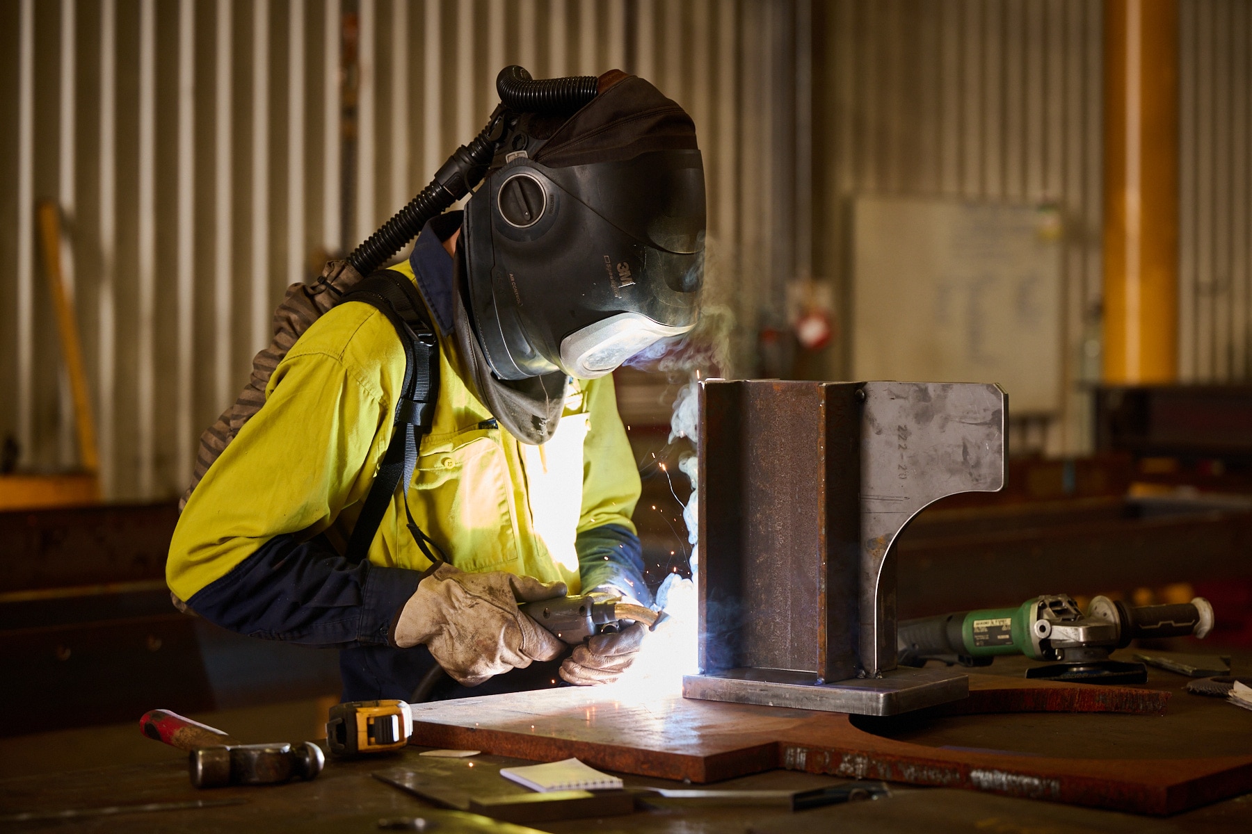 A person wearing a ventilation mask, gloves and protective gear welds metal